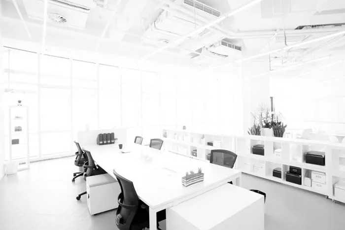 Bright white office with long workstations and storage shelving