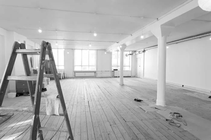 Empty commercial space after renovation with a ladder and new wood floors